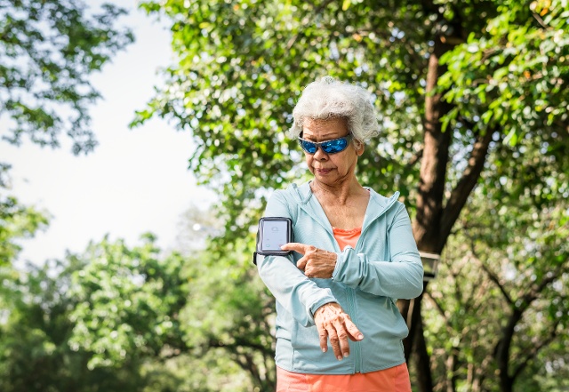 senior woman with phone armband outside 