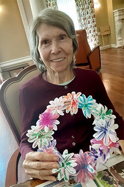 Senior woman with paper flower wreath in hand 