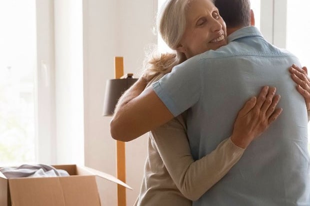 Older woman hugging man in front of box and light post 