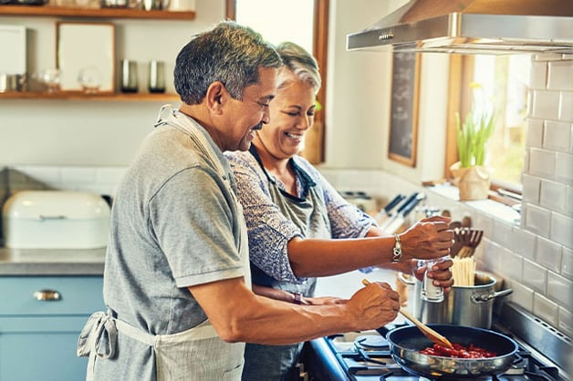 two people cooking sauce together over the stove