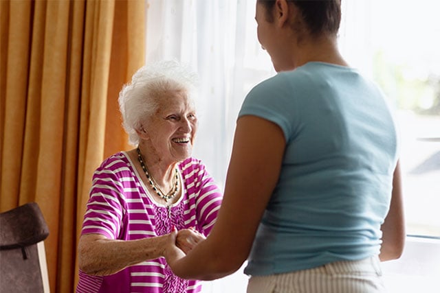 Woman helping older woman in chair