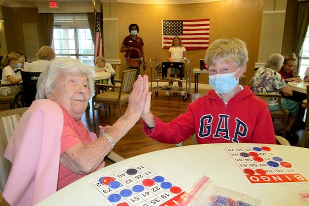 LIttle boy playing bingo with senior 