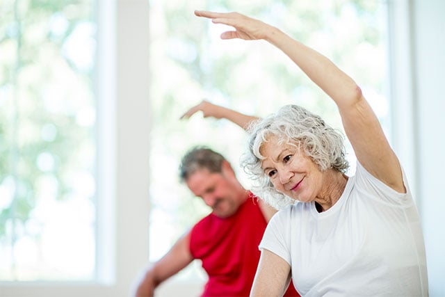 Relaxed senior woman practicing chair yoga